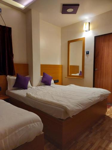 a hotel room with two beds and a mirror at Hotel Sai Dakshina Inn & The Fern Restaurant in Shirdi