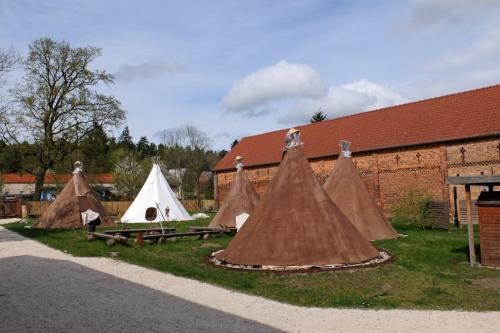 eine Gruppe von Zelten auf dem Rasen neben einem Gebäude in der Unterkunft Kuckunniwi Tipidorf in Werder