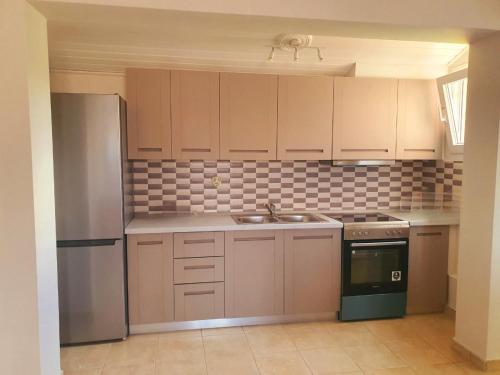 a kitchen with white cabinets and a sink and a refrigerator at BELLA De LUX APTS in Ýpsos