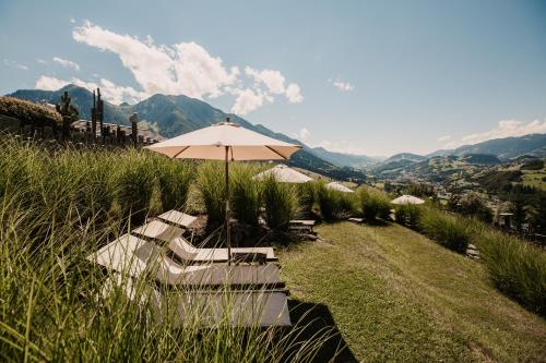a group of chairs and an umbrella on a hill at Chaletdorf BERGHERZ in Sankt Johann im Pongau