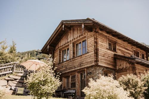 a large wooden house with windows and trees at Chaletdorf BERGHERZ in Sankt Johann im Pongau