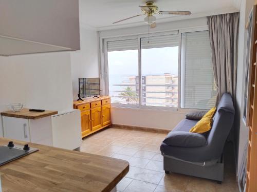 a living room with a couch and a kitchen at Acogedor estudio con vistas al mar 1ªLínea in Bellreguart