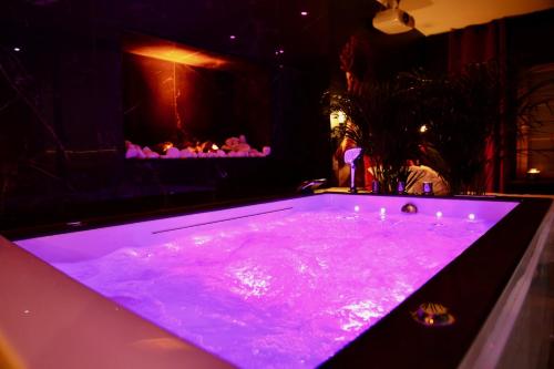 a purple bath tub in a room with a fireplace at love room gold - les delices rooms in Angers