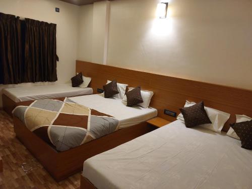 a room with three beds in a room with a window at Hotel Sai Dakshina Inn & The Fern Restaurant in Shirdi
