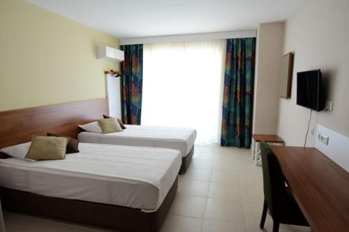 a hotel room with two beds and a television at KALİYE ASPENDOS HOTEL in Antalya