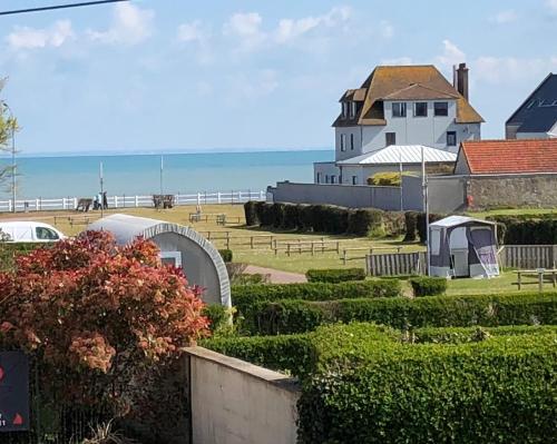 a house on the beach with the ocean in the background at La Maison des phares in Lion-sur-Mer