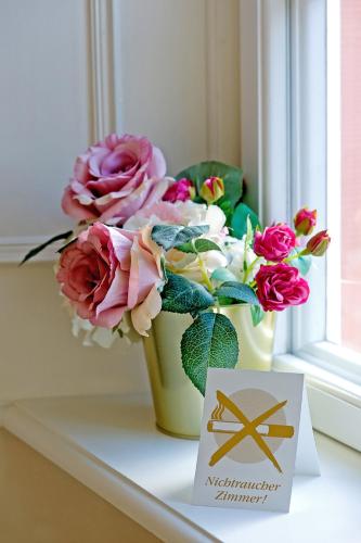 a vase with flowers on a window sill with a sign at SchlossHOTELGedern in Gedern