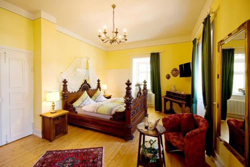 a bedroom with a bed and a chair and a chandelier at SchlossHOTELGedern in Gedern