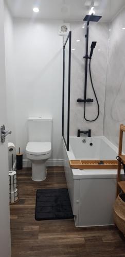 a bathroom with a tub and a toilet and a shower at Bowie's Abode in Sowerby Bridge
