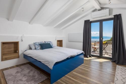 a bedroom with a blue bed and a balcony at Villa Lomida Opatija in Opatija