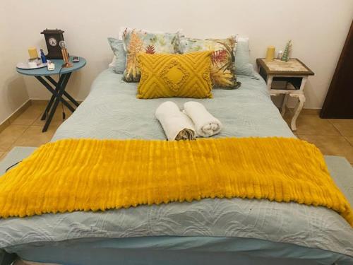 a bed with a yellow blanket and two towels at KleinHenties in Hentiesbaai