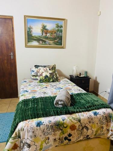 een slaapkamer met een bed met een groene deken bij KleinHenties in Hentiesbaai