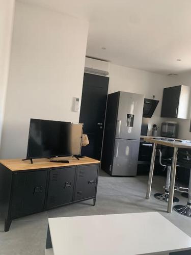 une pièce avec une cuisine avec une télévision et quelques tables dans l'établissement L' étoile de mer logement 3, à Sainte-Marie-la-Mer