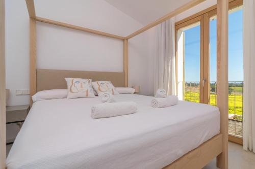 a bedroom with two beds and a large window at Can Mosca in Cala Mendia