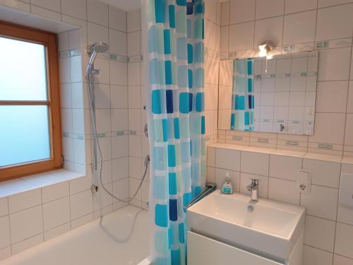 La salle de bains est pourvue d'un lavabo et d'une douche avec rideau de douche. dans l'établissement Wikasa, à Ofterschwang