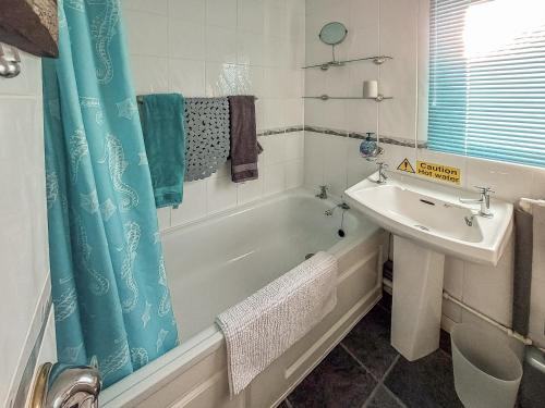 a bathroom with a tub and a sink and a bath tub at Casabella in Hemsby