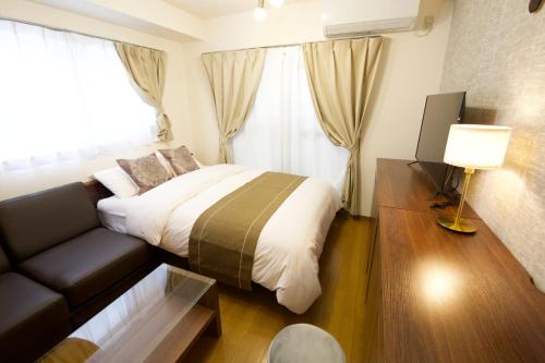 Habitación de hotel con cama y sofá en 大井町アパートメントホテル豊強ビル301 en Tokio