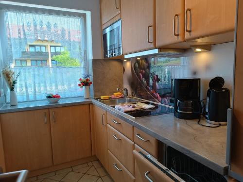 cocina con armarios de madera, fregadero y ventana en Bergblick-Seitz en Fischen