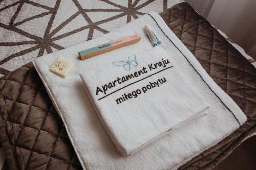 a towel with a thermometer and a toothbrush on a bed at Apartament Kraju centrum z fotelem masującym in Sosnowiec