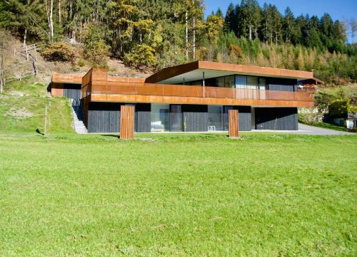una casa en una colina con un campo verde en Apartment GIDI und LISL, en Bramberg am Wildkogel