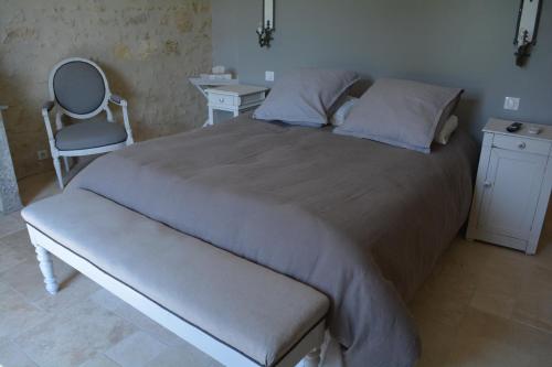 a bedroom with a large bed and a chair at la cabanne in Saint-Martin-Lacaussade