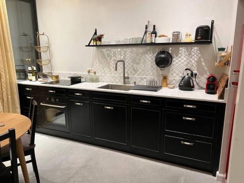 a kitchen with black cabinets and a sink at Rosa’s place in Jerusalem