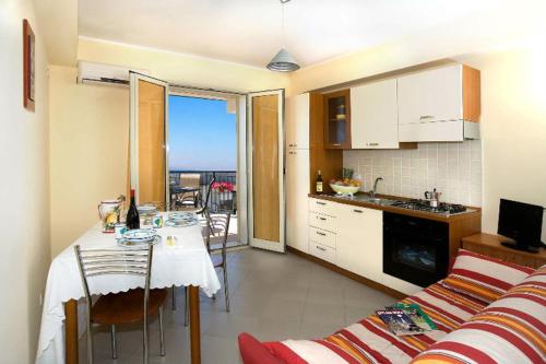 a kitchen and living room with a table and a couch at Riviera Ionica in Santa Teresa di Riva