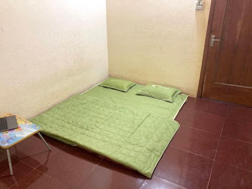 a small green bed in a room with a table at Cà Phê Dưới Hiên Nhà in Kon Von Kla