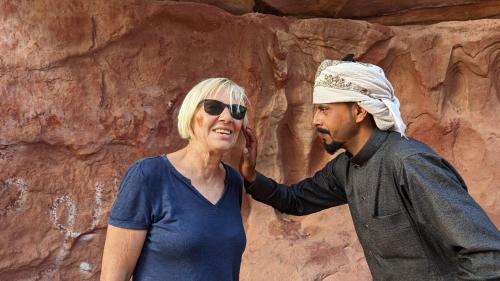 a man and a woman standing in front of a rock wall at Yara camp in Wadi Rum