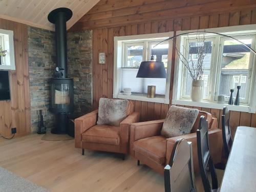 a living room with two chairs and a stove at Wonderful cabin with amazing mountain - view in Lifjell