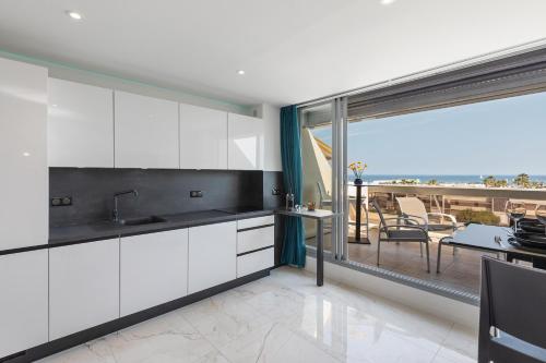 Il comprend une cuisine avec des placards blancs et offre une vue sur une terrasse. dans l'établissement Village Naturiste - Xcape Sea View Luxe, au Cap d'Agde