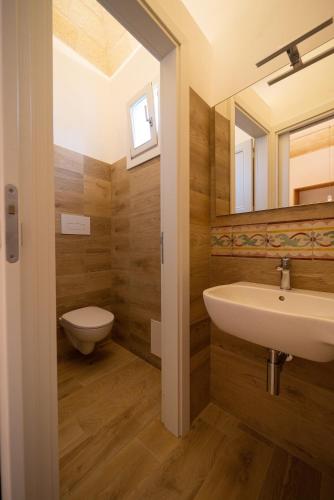 a bathroom with a sink and a toilet and a mirror at Butiko in Castelluzzo
