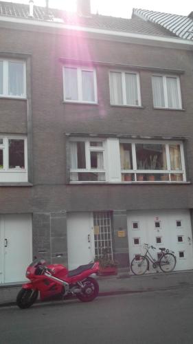 una motocicleta roja estacionada frente a un edificio en Merxotio en Ghent