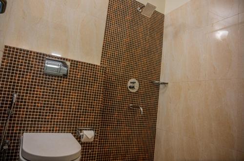 a bathroom with a toilet and a tiled shower at La Oasis by Meraden ,Goa in Anjuna