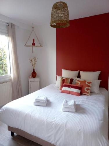 une chambre avec un grand lit blanc avec un mur rouge dans l'établissement Le Clos Beauséjour, à Montjean-sur-Loire