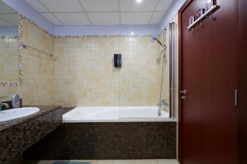 Charming spacious studio apartment in the heart of JBR By SWEET HOMES في دبي: حمام مع حوض استحمام ومغسلة