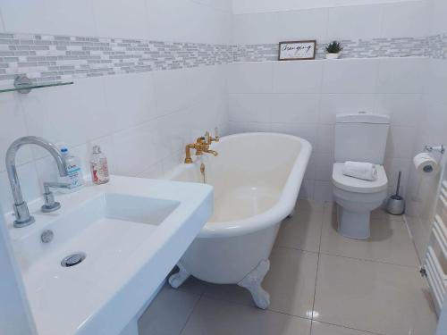 a white bathroom with a sink and a toilet at Corner House, Sleeps 8 in 4 Bedrooms, near train station, Great Value! in Manchester