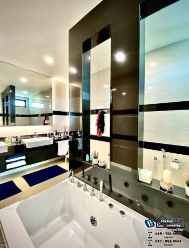 La salle de bains est pourvue d'une grande baignoire et d'un grand miroir. dans l'établissement Batu Ferringhi Luxurious Modern Designed 5BR House, à Batu Ferringhi