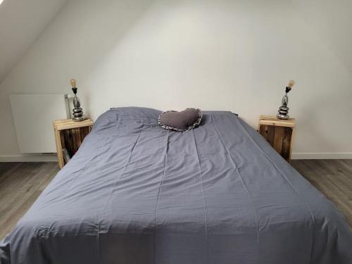 a bed with a purple comforter and two night stands at Appartement proche circuit in Changé