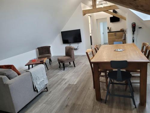 a living room with a table and chairs and a tv at Appartement proche circuit in Changé