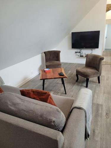 a living room with a couch and two chairs and a tv at Appartement proche circuit in Changé