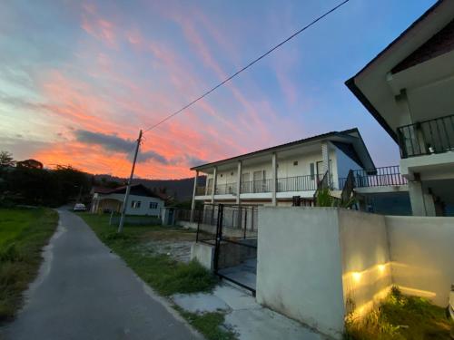 a house with a sunset in the background at LamanLeman Langkawi in Pantai Cenang