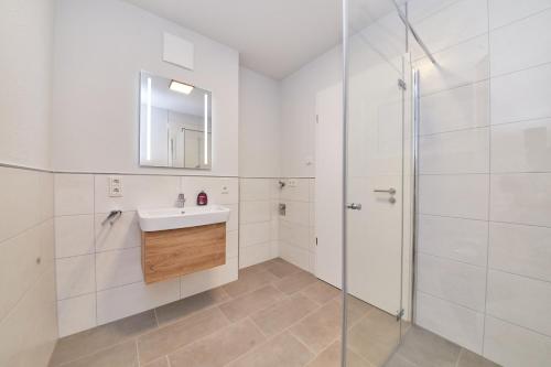La salle de bains blanche est pourvue d'un lavabo et d'une douche. dans l'établissement Fewo Jan & Henri, à Bernkastel-Kues
