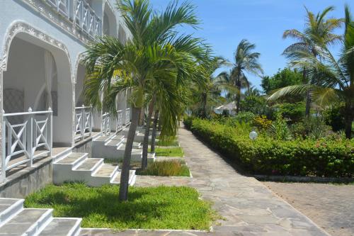 a palm tree next to a white building with stairs at Twiga Beach Resort in Watamu