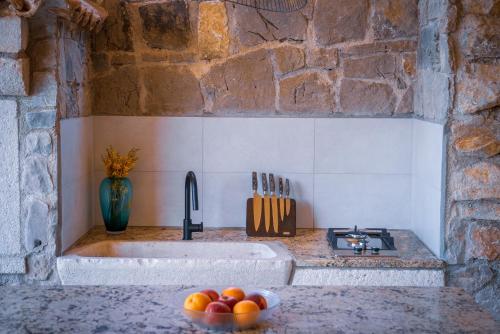 a kitchen with a sink and a bowl of fruit on a counter at KUĆA OD SOLI in Sveti Jakov