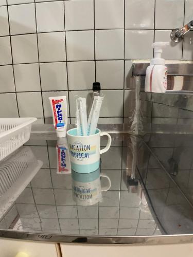 a cup of toothbrushes sitting on a glass shelf at The Mickey Carlton Ohashi 107 in Shiobaru
