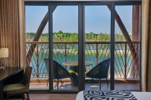 a room with a balcony with chairs and a table at Lapita, Dubai Parks and Resorts, Autograph Collection in Dubai
