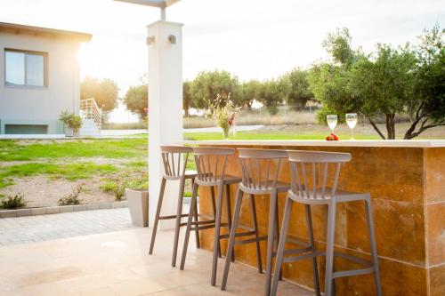 a patio with a bar with chairs and wine glasses at Alikon Adult-Only in Neos Marmaras