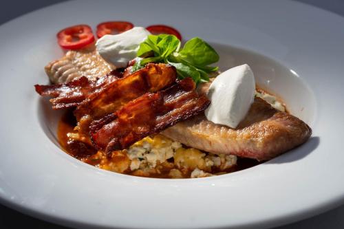 a white bowl of food with bacon and rice at Teátrum Boutique Hotel in Győr