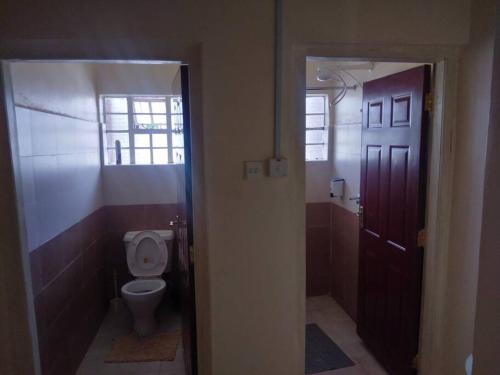 a bathroom with a toilet and a window and a door at La petals hideaway house-Machakos in Machakos